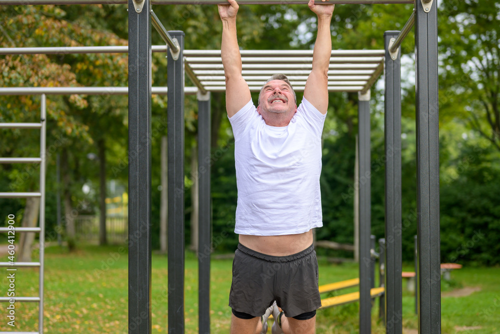 Senior man working out on parallel bars in a park in spring