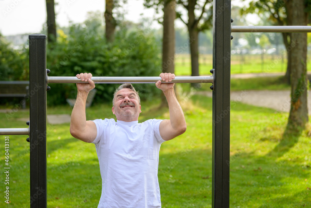 Senior man straining to pull himself up by the arms Senior man straining to pull himself up by the arms