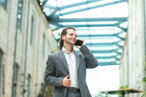A young successful businessman is working outdoor using smartphone. Man in a casual wear. Business, freelance and remote work.