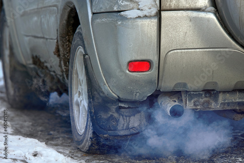 Car engine smoking, smoking exhaust pipe, closeup. Blue exhaust smoke. Car with gasoline or diesel  engine. Engine warming up at idle in winter season. photo