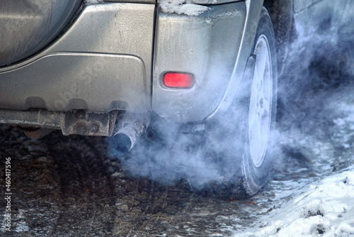 Blue exhaust smoke. Car engine smoking. Smoking exhaust pipe, closeup. Car with gasoline or diesel engine. Engine warming up at idle in winter season photo