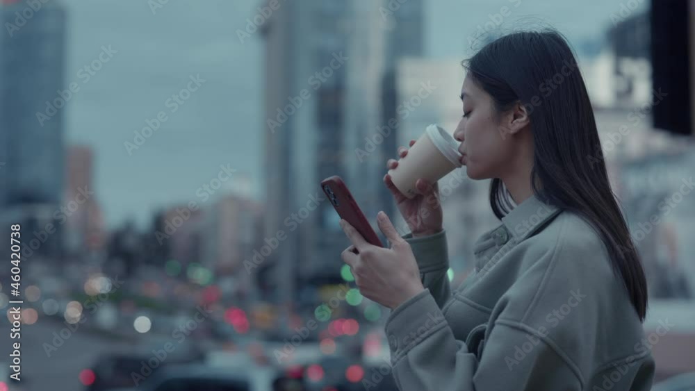 Young woman drinking coffee and using mobile outdoors
