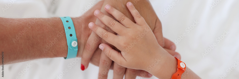 Hands of parents and child with bracelet are joined together Hands of parents and child with bracelet are joined together