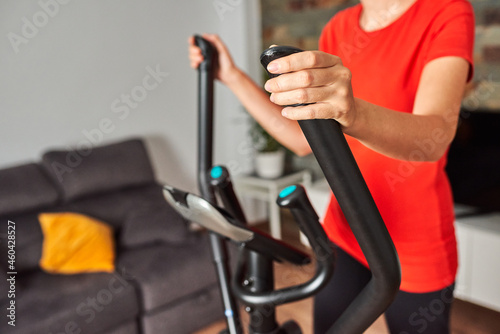 Unrecognizable woman training at home using the elliptical trainer