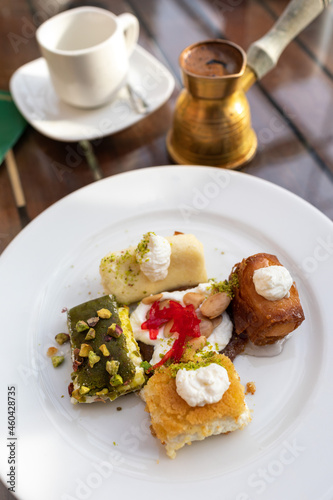 Tripoli, Lebanon, January 19, 2019, various traditional oriental sweets on a plate, Lebanese cuisine, a cup of coffee and a coffee turka (coffee pot).