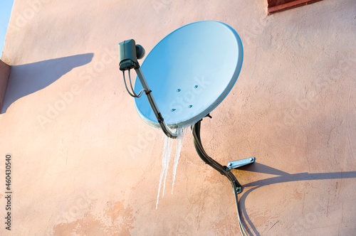 Satellite dish on the wall of the house in winter.
