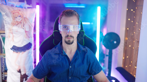 Attractive man geek portrait in gaming room with neon lights and dakimakura in background