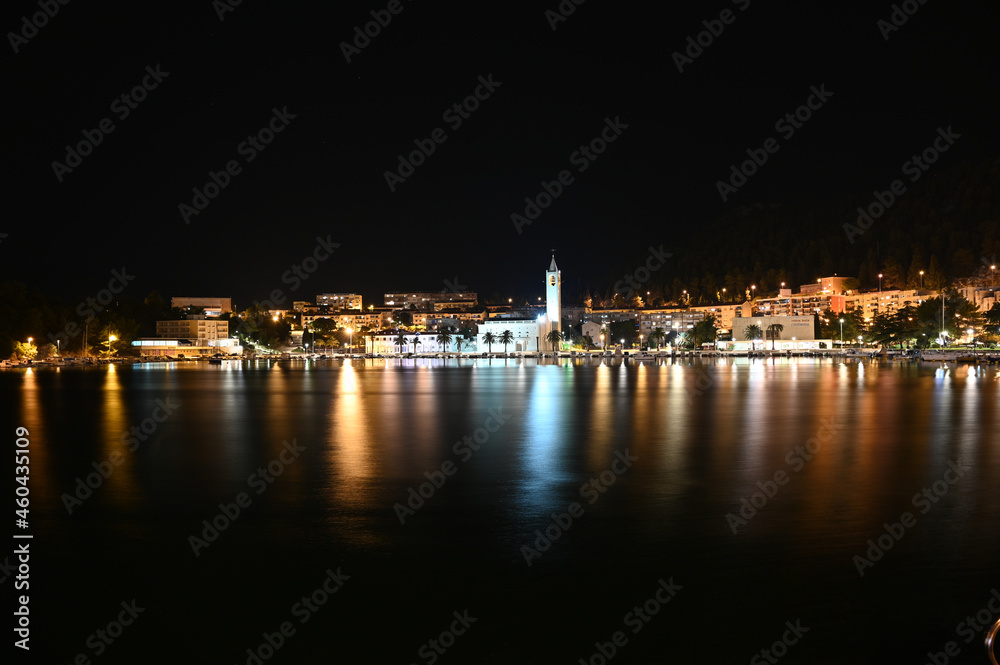 City of Ploce and Adriatic sea in Croatia by night. Panoramic view of  buildings in town reflected in the water. 