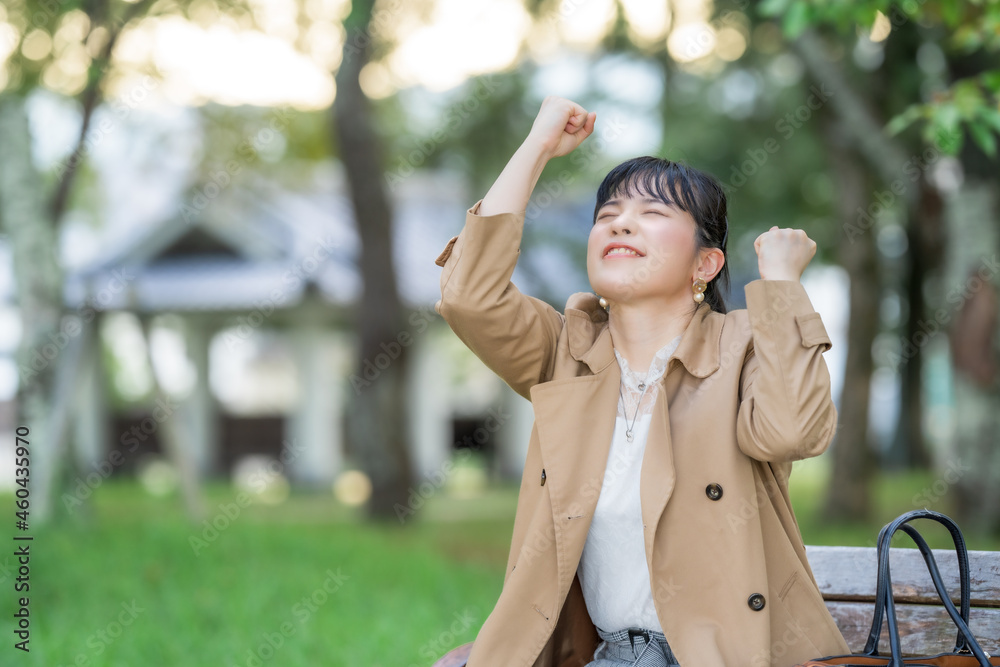 公園のベンチでガッツポーズする女性 Stock Photo Adobe Stock