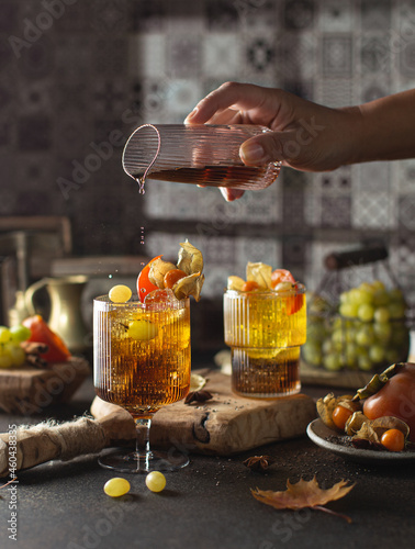 Healthy cocktail with maple syrup,grape juice,chia seeds,physalis,persimmon and cinnamon on the kitchen table with shadow of the window and vintage dishes.Freeze motion. © Olga_arisphoto