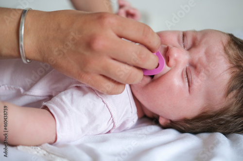 mothers hand give nipple to little crying baby girl. Happy family