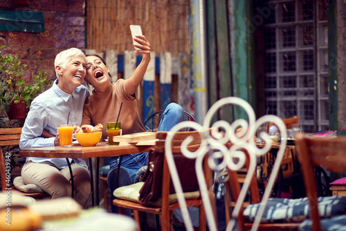 mother and daughter concept. young adult caucasian female and elderly woman taking selfie with cell phone, smiling.