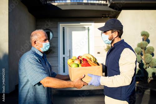 Tablou pe pânză Senior man accepting food delivery from deliveryman during covid19 pandemic or lockdown
