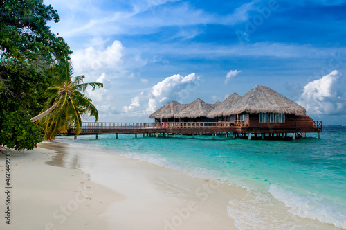 Water bungalow on the islands of the Maldives, a beach with palm trees and azure water. Vacation concept, travel to Paradise Beach in Maldives. A hotel in a tropical paradise.
