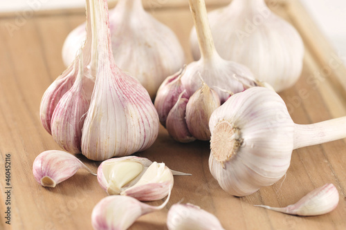 young garlic - whole garlic heads and slices on a wooden board