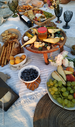 Picnic in nature with cute women's decorations. Fruits, wine, cheese, treats and candles