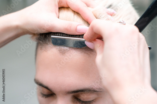 straight razor. haircut process of blond young man in barbershop salon