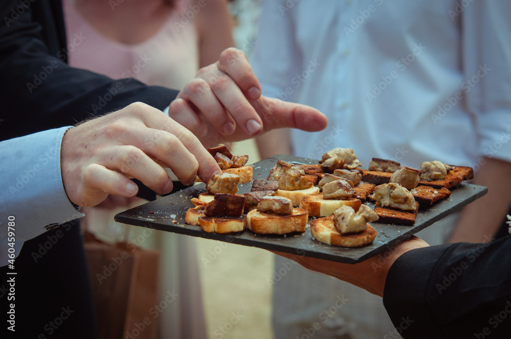 Toasts de foie gras chaud - les mains prennent les mise en bouche sur un plateau lors d'une célébration