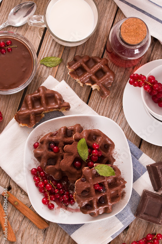 Waffles with chocolate topping, red currant and hazelnuts.