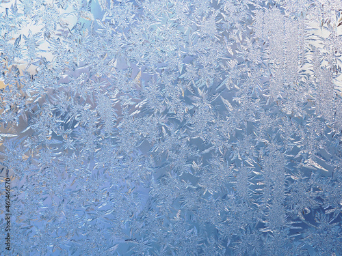 Winter light white and blue background or wallpaper. Drawing of crystals of ice and frost on the window pane. Abstract Christmas and New Year backdrop