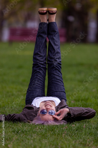 Young blonde with blue eyes in the park on green grass flirts with the camera photo