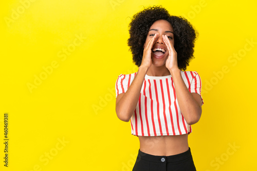 Young African American woman isolated on yellow background shouting and announcing something