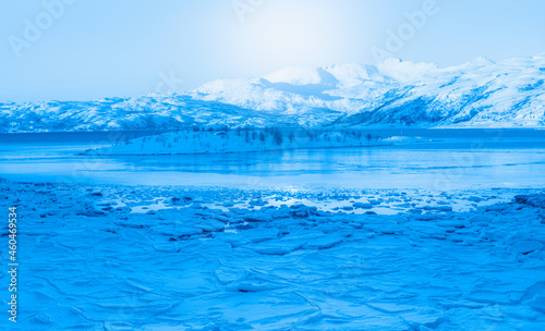 Panoramic view at fjord with coast of the Norwegian Sea in the background snowy mountains Arctic Circle at sunset - As a result of melting snow, freezing of the water mixed with the sea -Norway © muratart