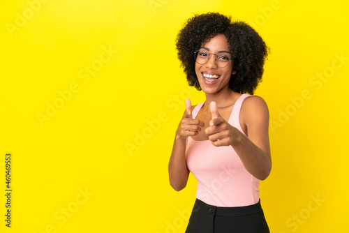 Young African American woman isolated on yellow background pointing to the front and smiling