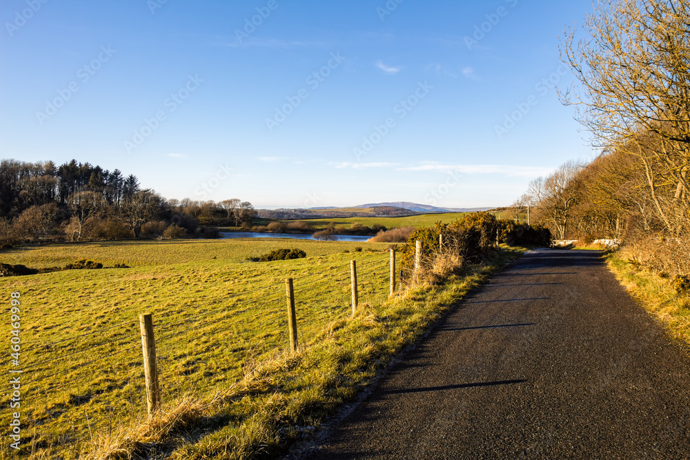 A countryside rural road and lake on a sunny winter day in Scotland