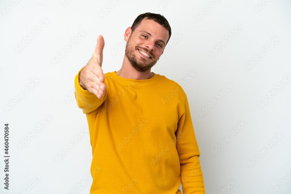 Young Brazilian man isolated on white background shaking hands for closing a good deal