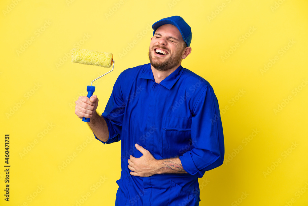 Painter Brazilian man isolated on yellow background smiling a lot