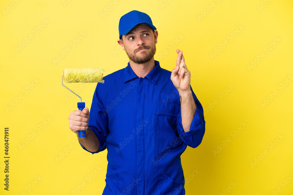 Painter Brazilian man isolated on yellow background with fingers crossing and wishing the best Painter Brazilian man isolated on yellow background with fingers crossing and wishing the best