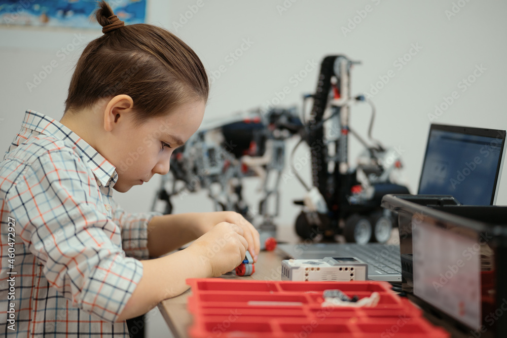 Boy Works on a Fully Functional Programable Robot for His School Robotics Club Project.