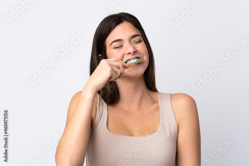 Teenager Brazilian girl brushing her teeth over isolated white background