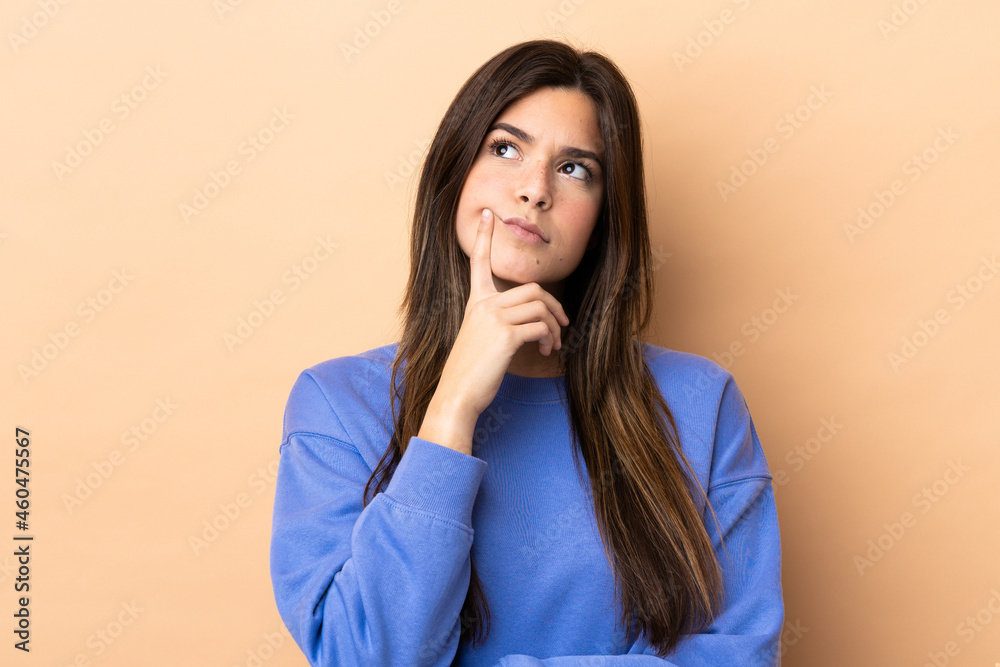 Teenager Brazilian girl over isolated background having doubts while looking up Teenager Brazilian girl over isolated background having doubts while looking up