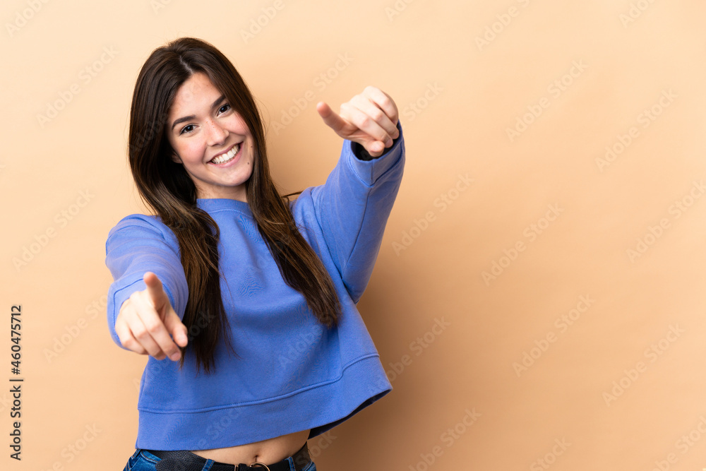 Teenager Brazilian girl over isolated background pointing front with happy expression Teenager Brazilian girl over isolated background pointing front with happy expression