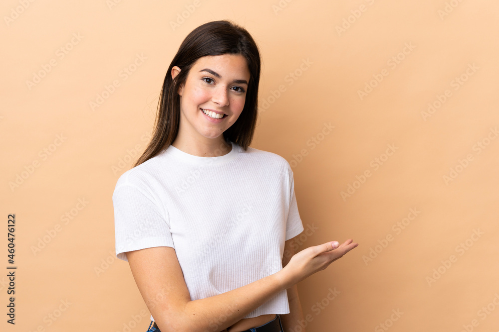 Teenager Brazilian girl over isolated background presenting an idea while looking smiling towards Teenager Brazilian girl over isolated background presenting an idea while looking smiling towards