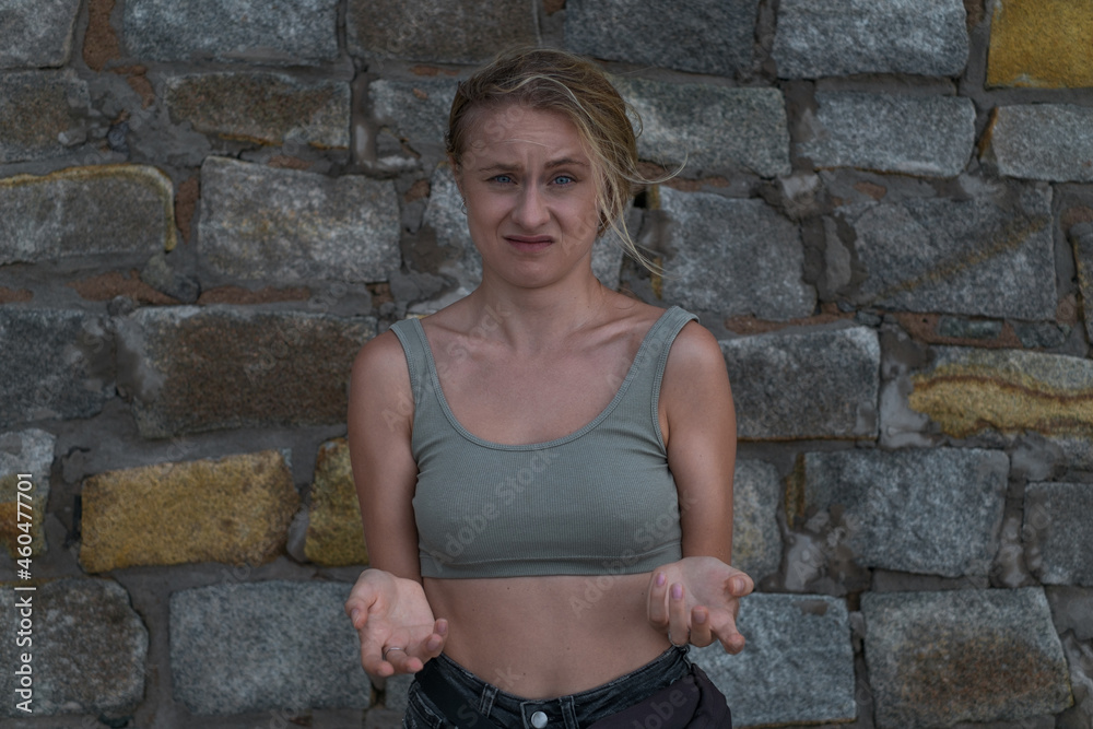 Misunderstood surprised face of young caucasian woman in crop top on the stone background. Concept of human emotions, facial expression. Misunderstood surprised face of young caucasian woman in crop top on the stone background. Concept of human emotions, facial expression.