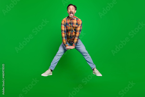 Full length body size view of attractive cheerful man jumping having fun fooling isolated over bright green color background