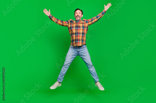 Full length body size view of attractive cheerful man jumping having fun good mood isolated over bright green color background