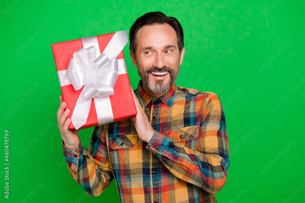 Portrait of attractive cheerful man curious holding in hands giftbox guessing what inside isolated over bright green color background Portrait of attractive cheerful man curious holding in hands giftbox guessing what inside isolated over bright green color background