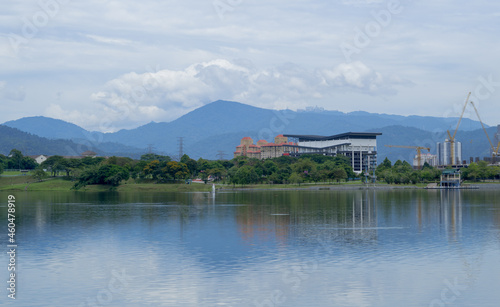 Landscape of Kepong lake in Kuala Lumpur during sunny day with reflection on water  clouds and mountains in the background. 