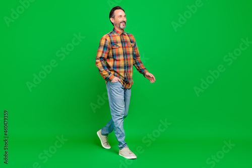 Full length body size view of attractive cheerful man going wearing cozy clothes isolated over bright green color background