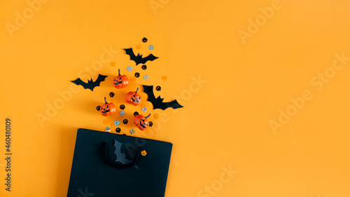 Halloween pumpkins, bats, party objects and shopping bag flat lay. Top view, copy space. 