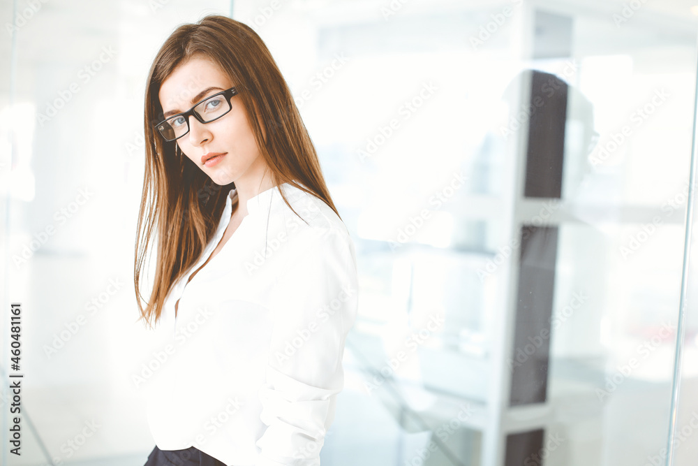 Beautiful female specialist with dark hair standing in modern office and smiling charmingly. Working on design, data analysis, plan strategy. Business people concept Beautiful female specialist with dark hair standing in modern office and smiling charmingly. Working on design, data analysis, plan strategy. Business people concept