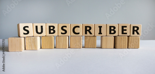 Subscriber symbol. The word Subscriber on wooden cubes. Beautiful white table, white background. Business and subscriber concept. Copy space.