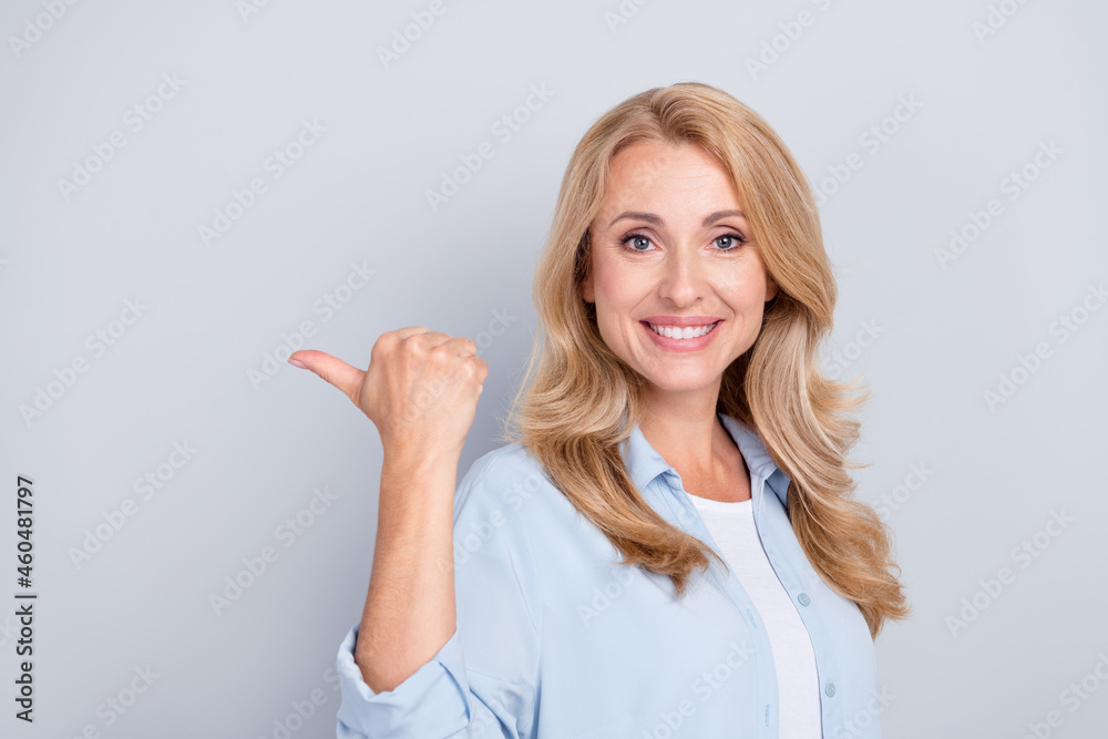 Portrait of smiling good looking girl point finger thumb copyspace advertisement isolated on grey color background Portrait of smiling good looking girl point finger thumb copyspace advertisement isolated on grey color background