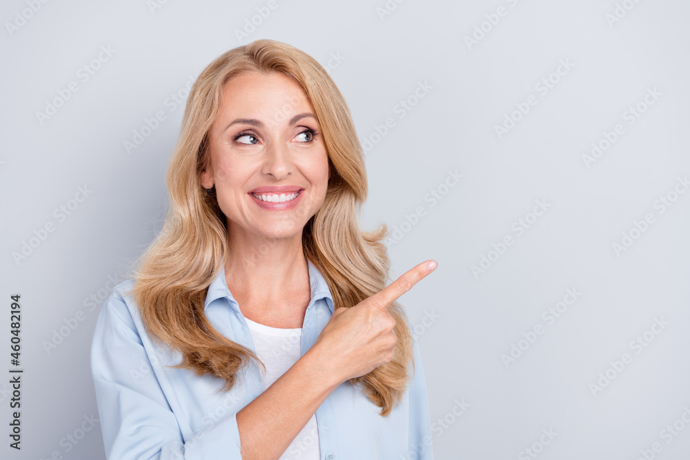 Photo of smiling cheerful young female look copyspace advertise product sale discount isolated on grey color background Photo of smiling cheerful young female look copyspace advertise product sale discount isolated on grey color background