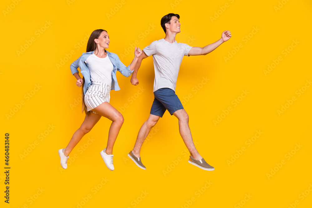 Full length body size view of handsome beautiful couple jumping running good mood isolated over vivid yellow color background