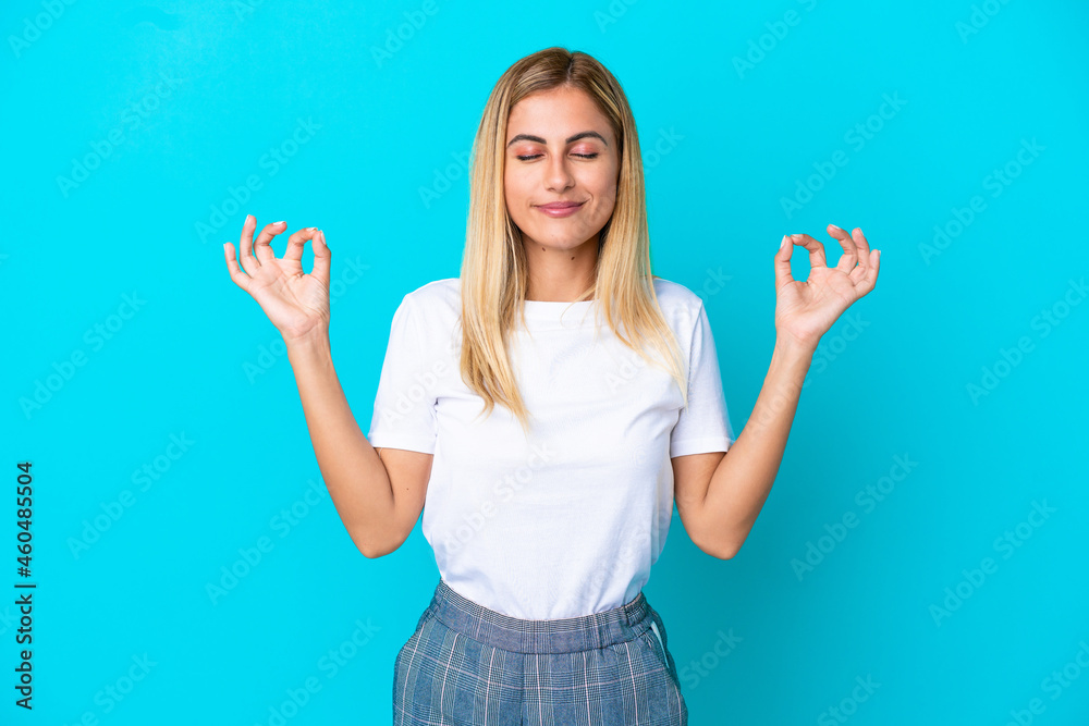 Blonde Uruguayan girl isolated on blue background in zen pose Blonde Uruguayan girl isolated on blue background in zen pose